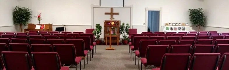 The sanctuary at Grace Gospel Fellowship, with rows of red chairs facing a wooden cross and pulpit